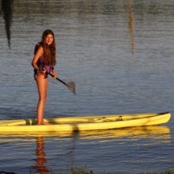 A young female camper paddle boarding on Lake Livingston.