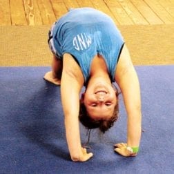 A young camper practicing a gymnastics routine on a mat.