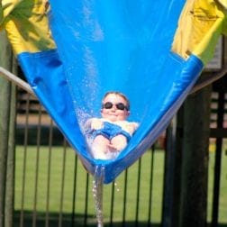 A young male camper riding the water slide at the Camp Olympia pool.