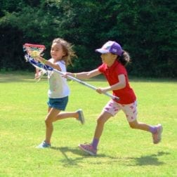 Two female campers competing in a game of lacrosse.