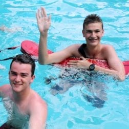 Two male students in a pool taking a lifeguard certification test.