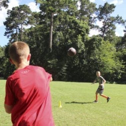 A young football player throwing a pass to another player during practice.