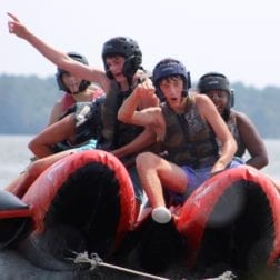 Four male campers riding the inflatable rocket on Lake Livingston.