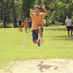 A young camper in midair while competing in the long jump.