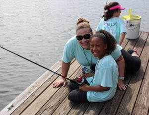 Girl camper fishing on a dock