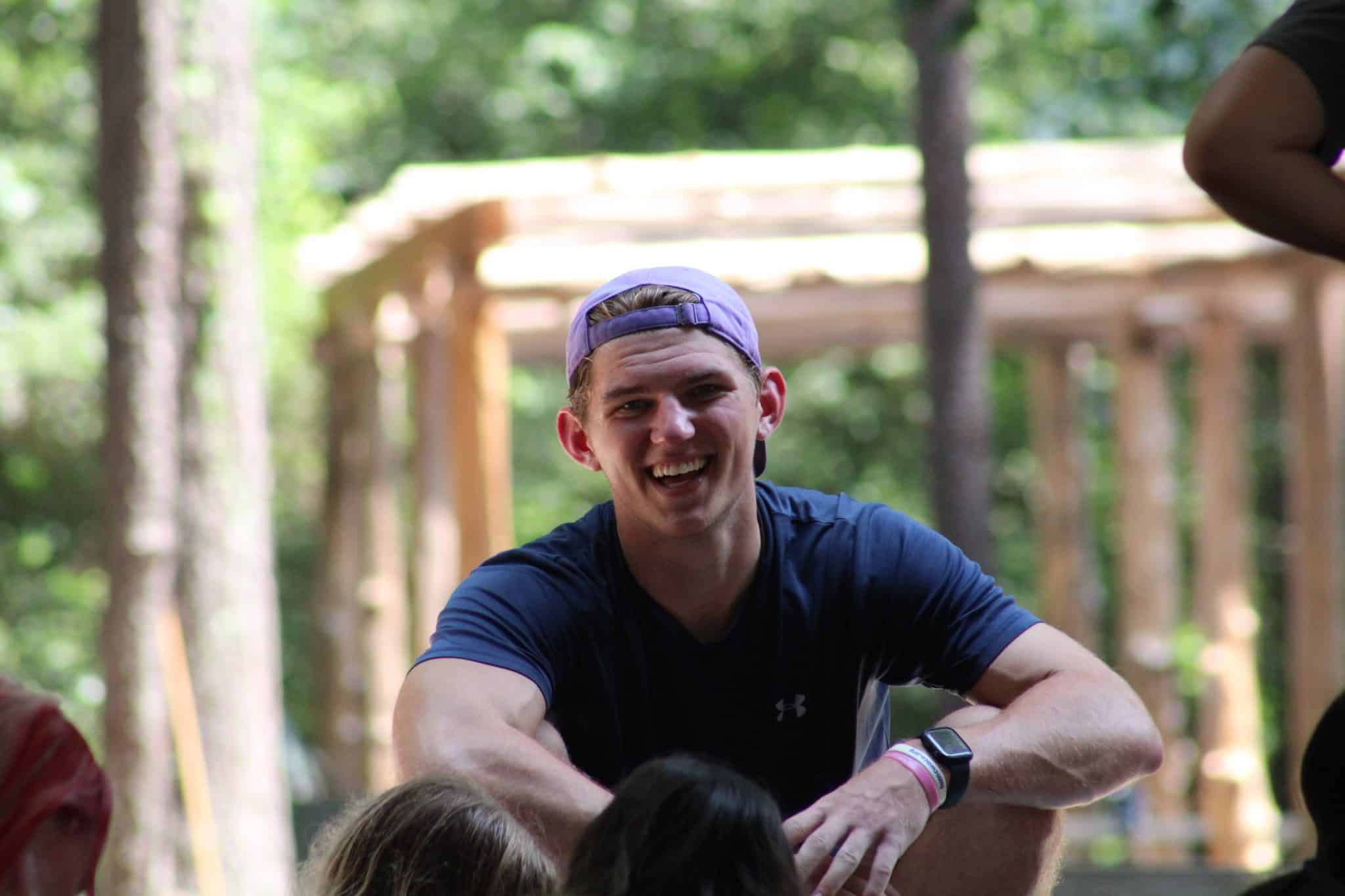 male summer camp counselor smiling at crowd of campers