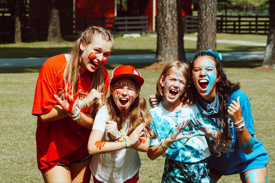 Two campers and two camp counselors wearing red and blue camp colors and face paint.