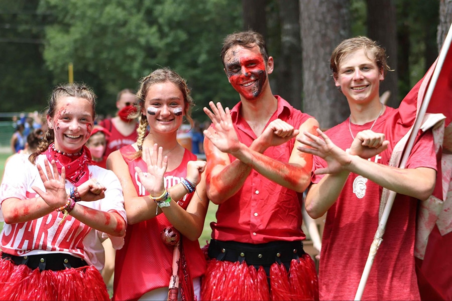 Two campers and two camp counselors wearing red Spartan camp colors and face paint.