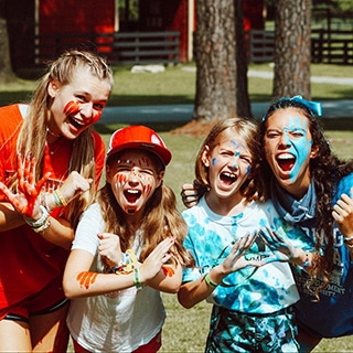 Two campers and two camp counselors wearing red and blue camp colors and face paint.