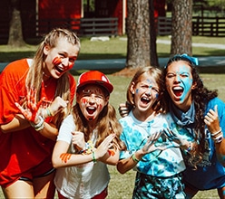 Two campers and two camp counselors wearing red Spartan and blue Athenian camp colors.