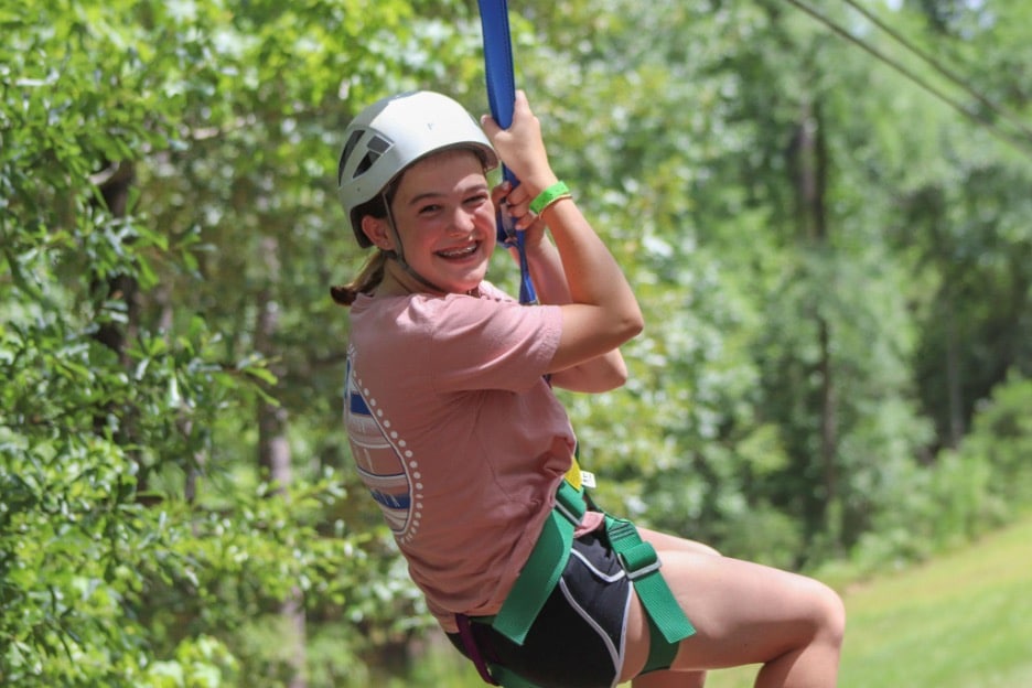 Smiling young girl on a zipline at Camp Olympia