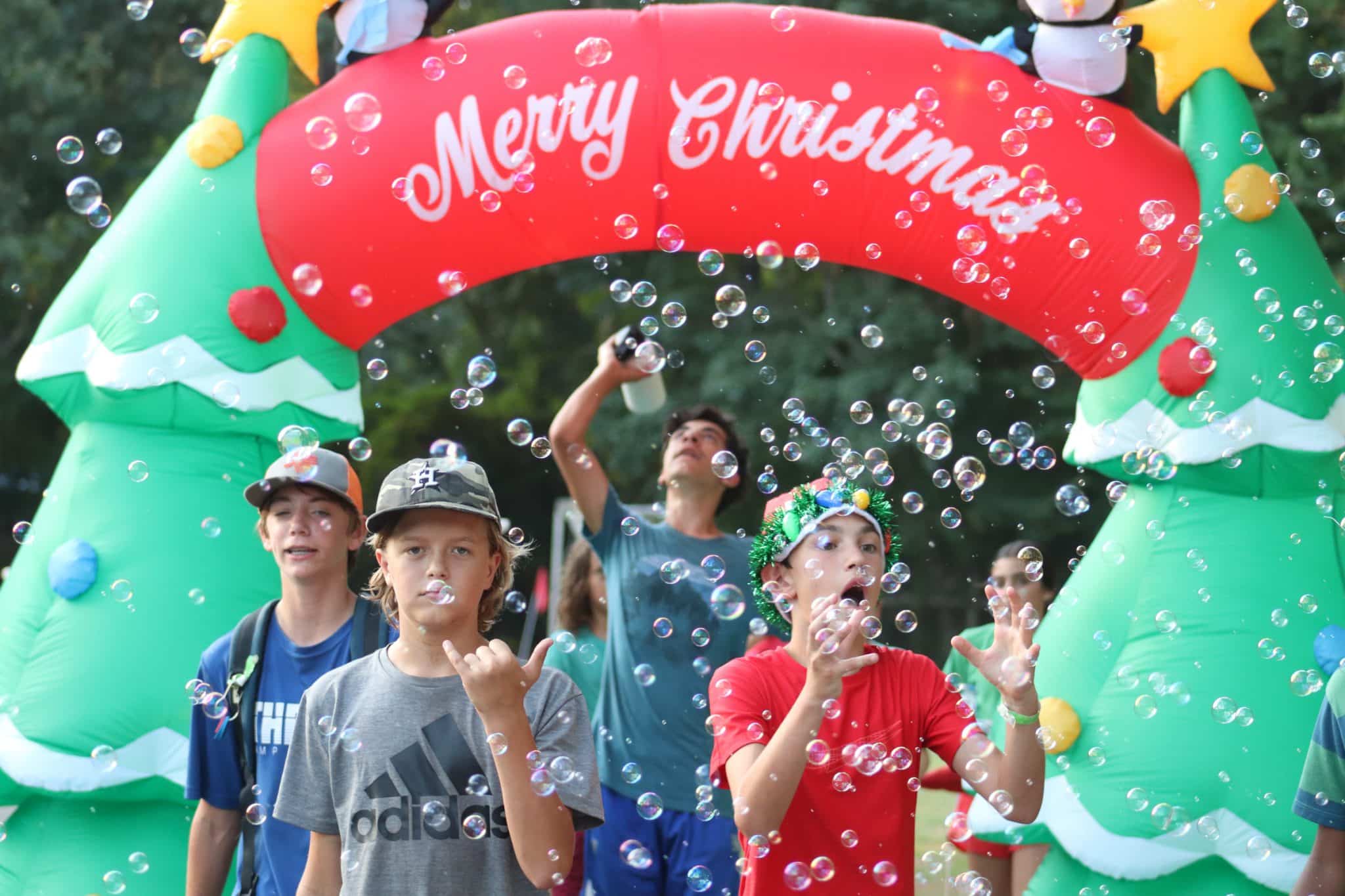 Camp Olympia campers walking through Christmas inflatable and bubbles.