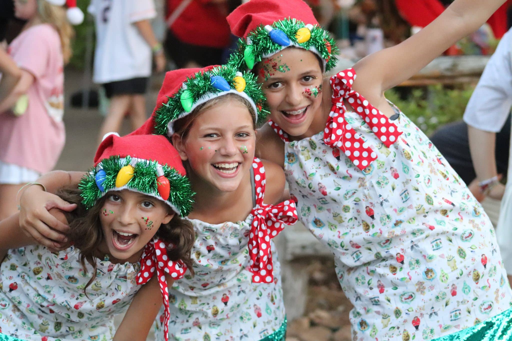 Girl campers dressed in matching Christmas outfits and hats.